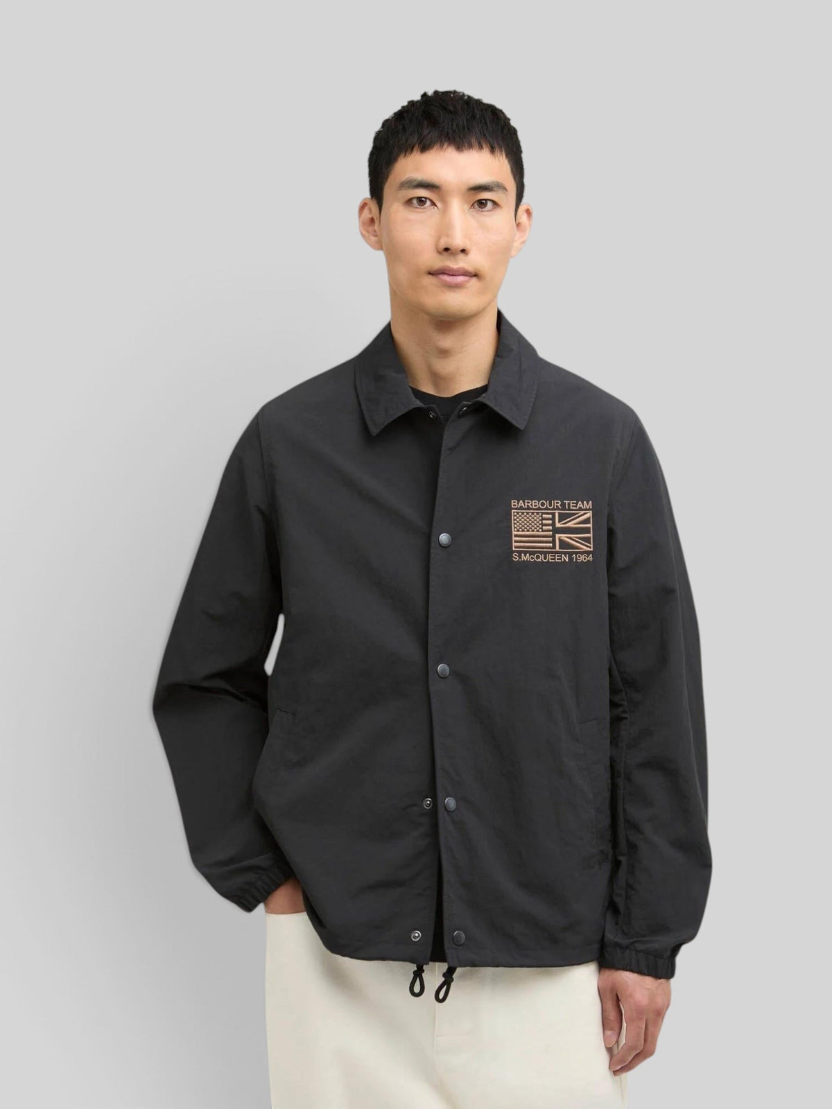 Baffle Haus black coach jacket with stud front, sit-down collar, and Steve McQueen embroidery on the chest.