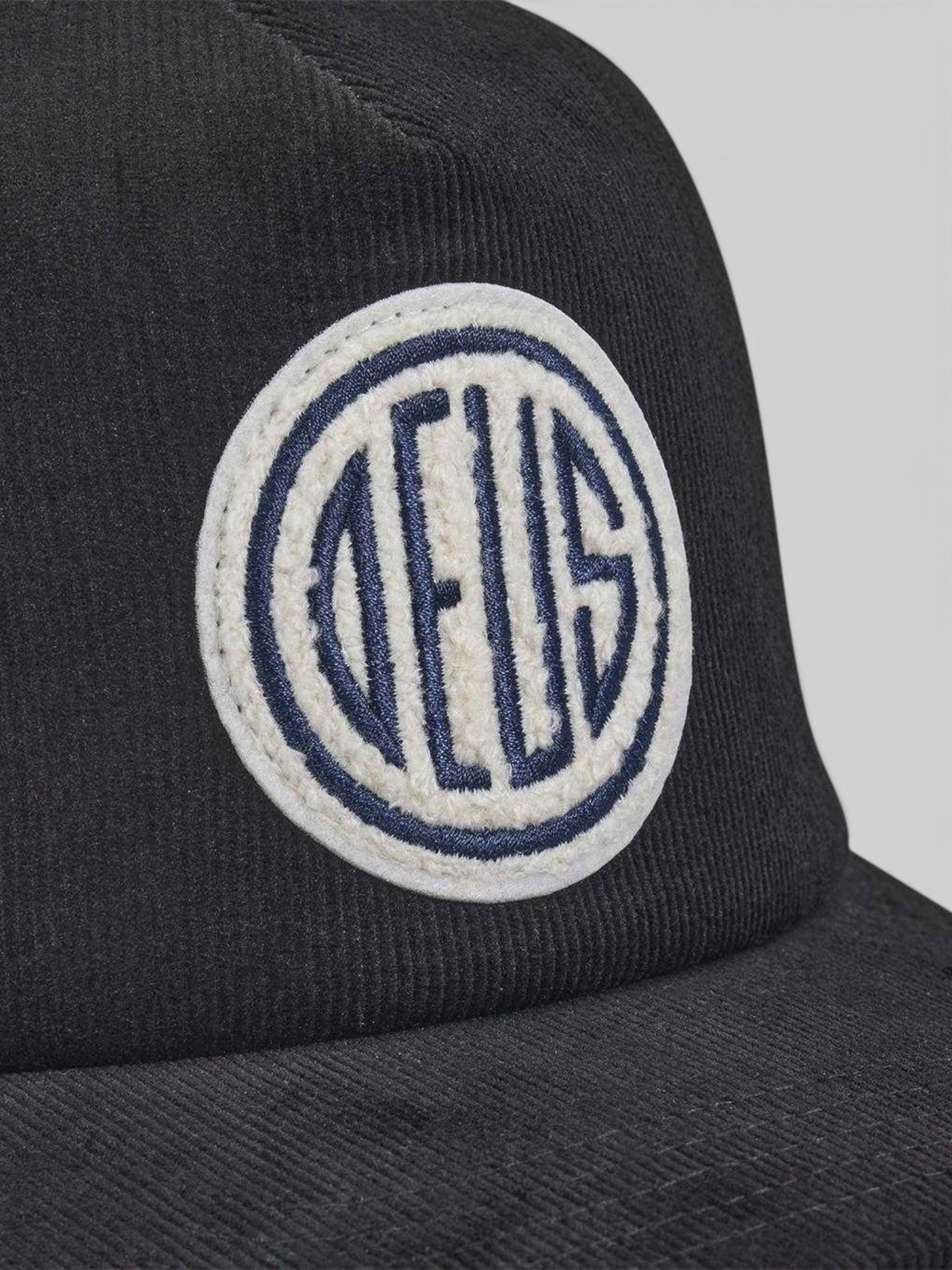 Baffle Haus black cotton corduroy trucker hat featuring a circular embroidered logo patch on the front panel.