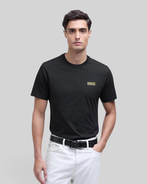 Baffle Haus black cotton crew neck t-shirt with small yellow chest logo worn by a male model with white jeans