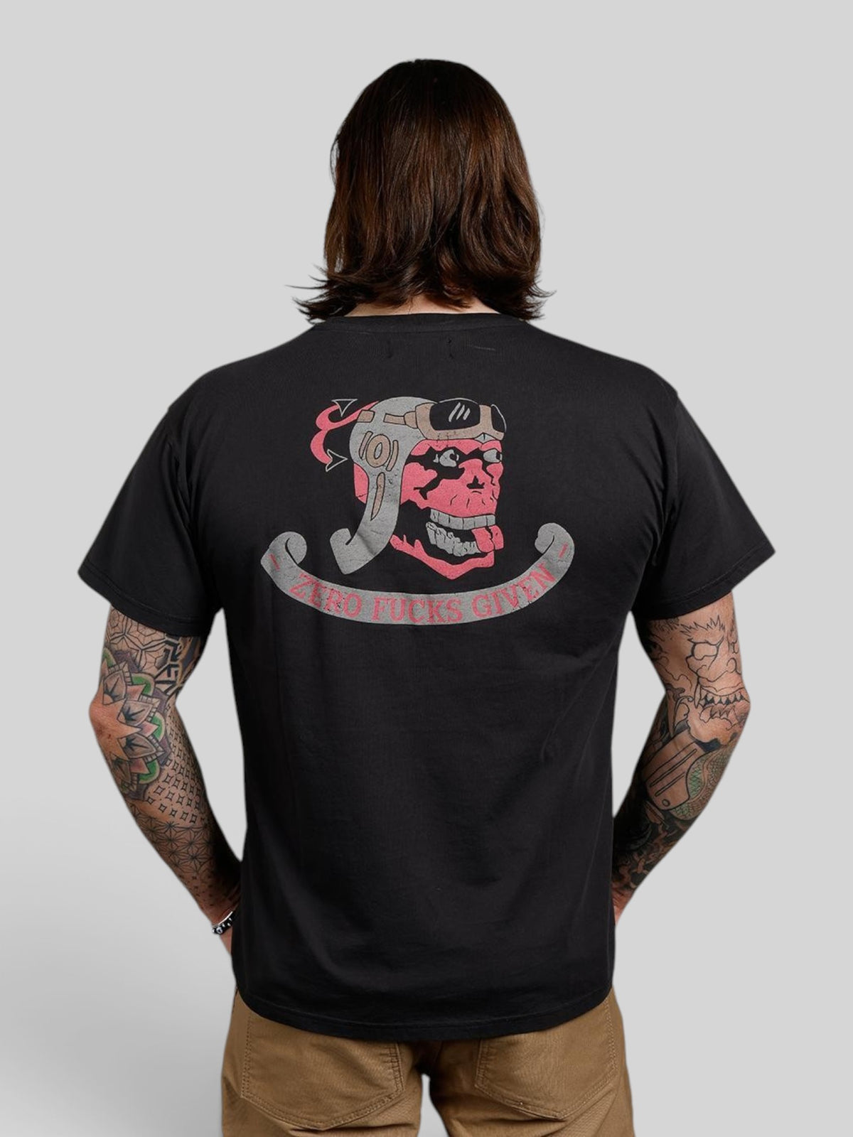 Baffle Haus black 100% cotton t-shirt with a vintage skull pilot graphic on the back, worn by a tattooed man.