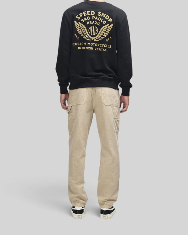 Baffle Haus Munificence Crew black fleece with gold graphic print on back worn with beige cargo trousers