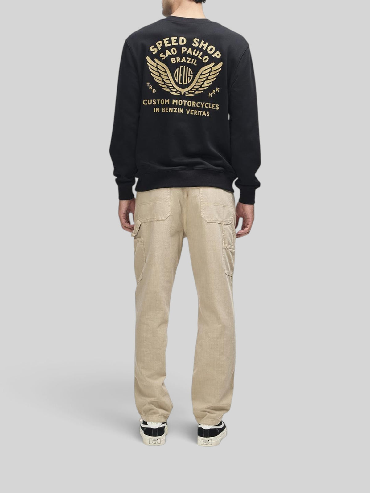 Baffle Haus Munificence Crew black fleece with gold graphic print on back worn with beige cargo trousers