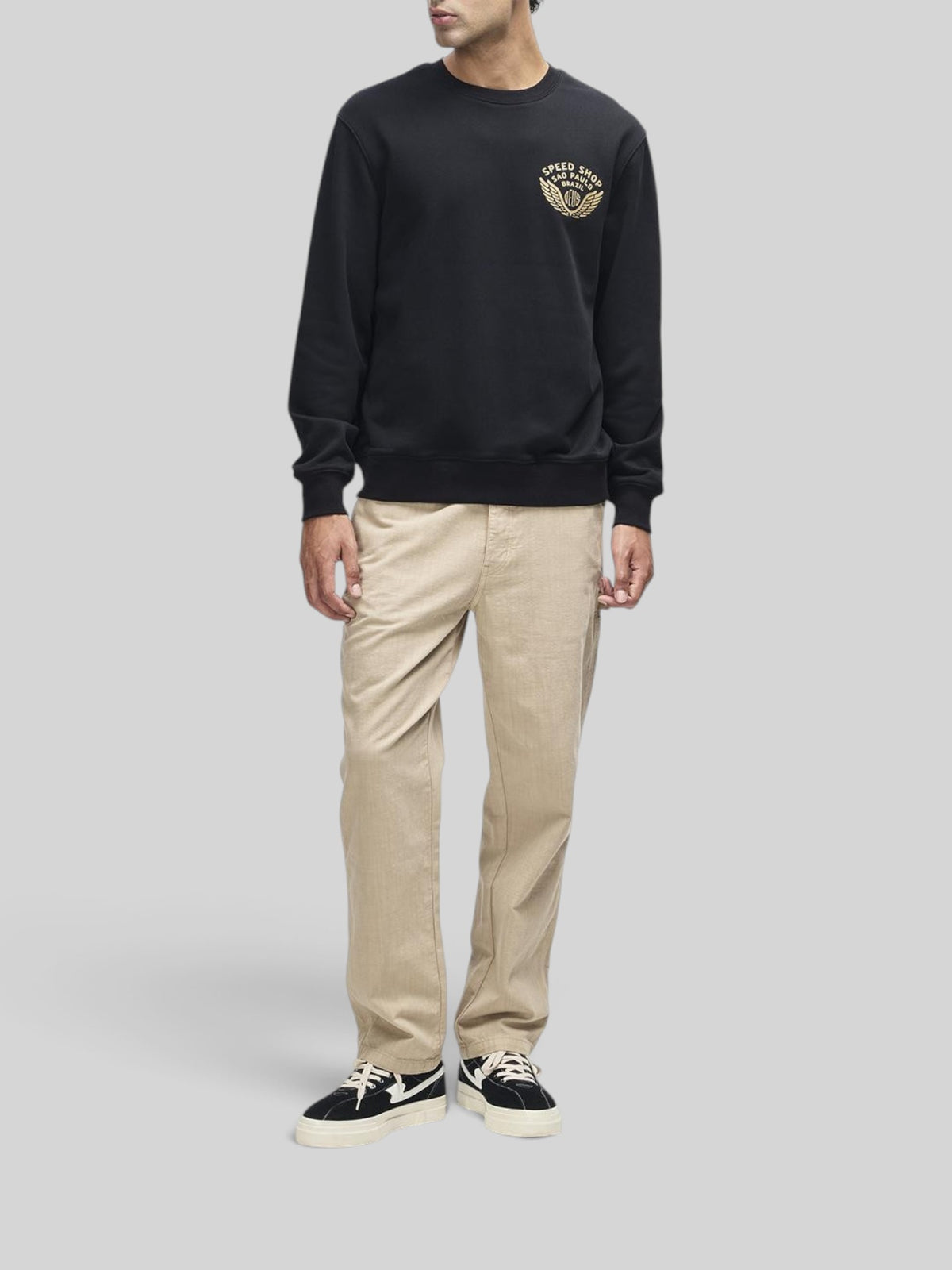 Baffle Haus Munificence crew neck fleece in black with chest graphic, ribbed cuffs, and hem on a male model.