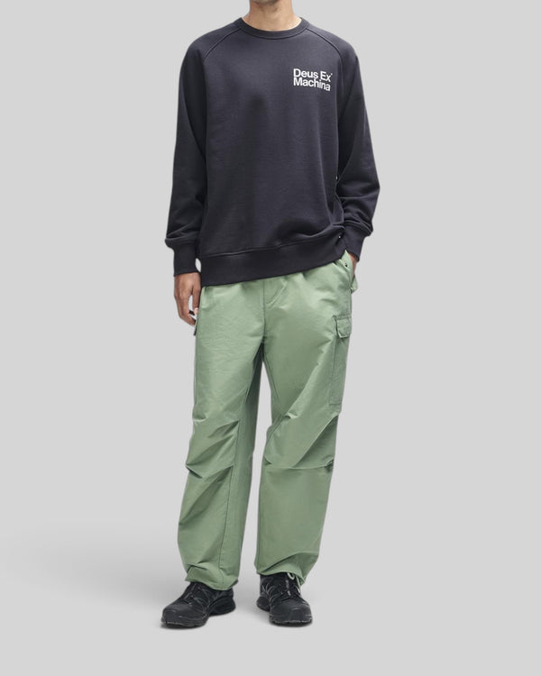 Baffle Haus Plenty Good Crew in black with chest print, worn with loose fit sage green cargo pants.