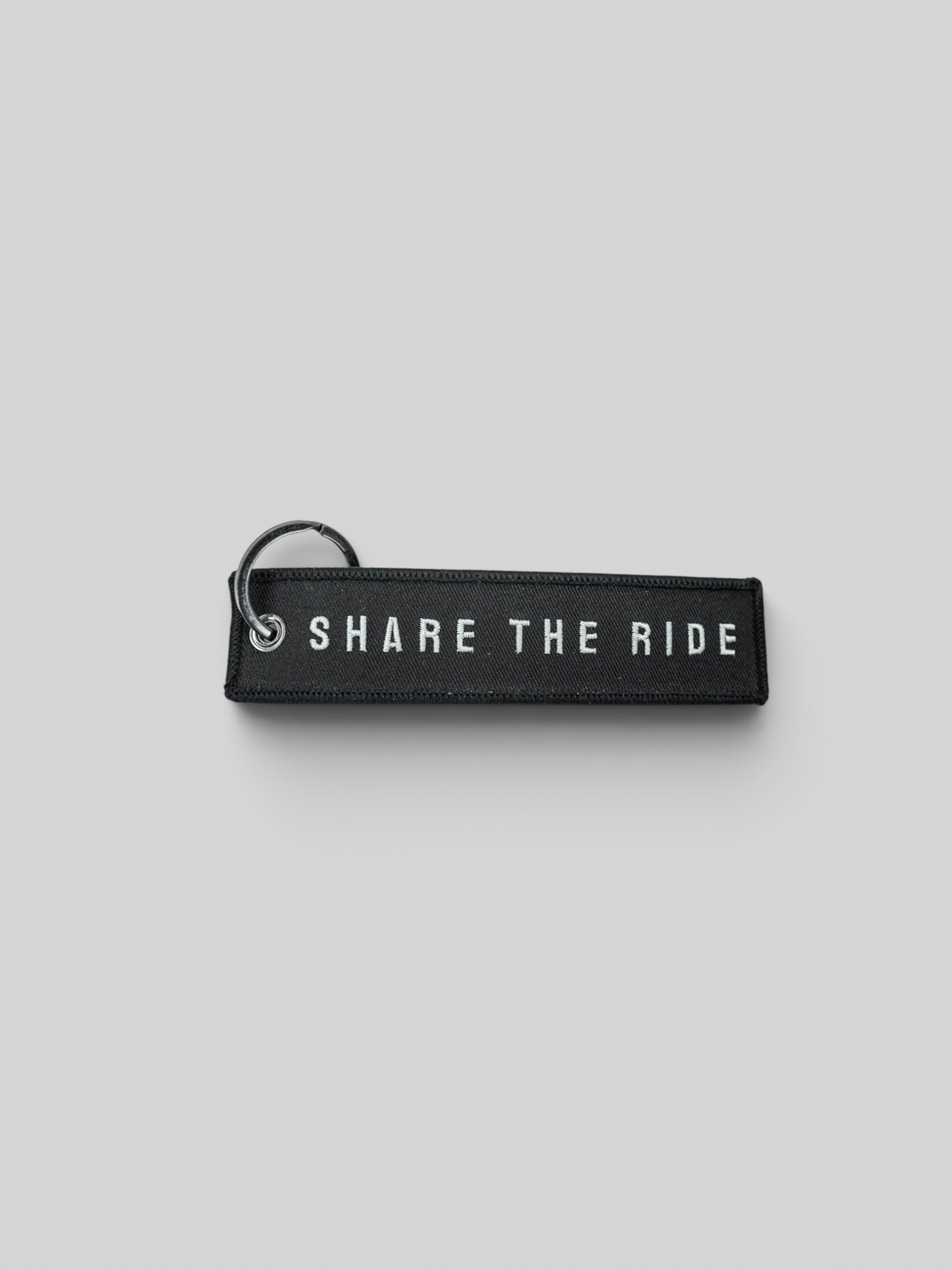 Baffle Haus black embroidered keyring featuring the text Share The Ride with a durable metal attachment