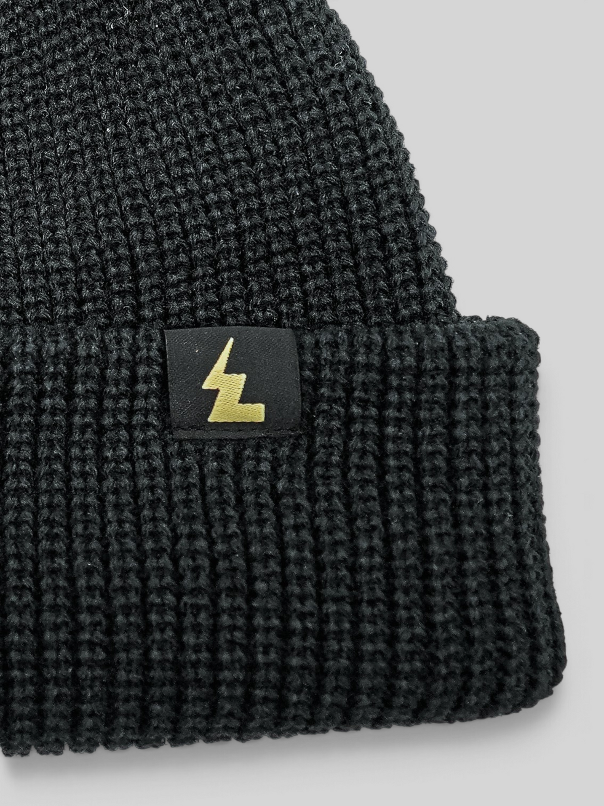 Baffle Haus black fisherman beanie with a ribbed knit texture and a small woven logo label on the cuff.