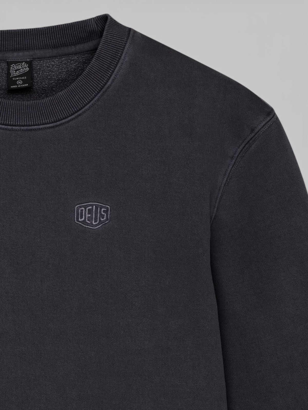 Baffle Haus black garment dyed crew neck sweatshirt with embroidered Deus shield logo on the chest
