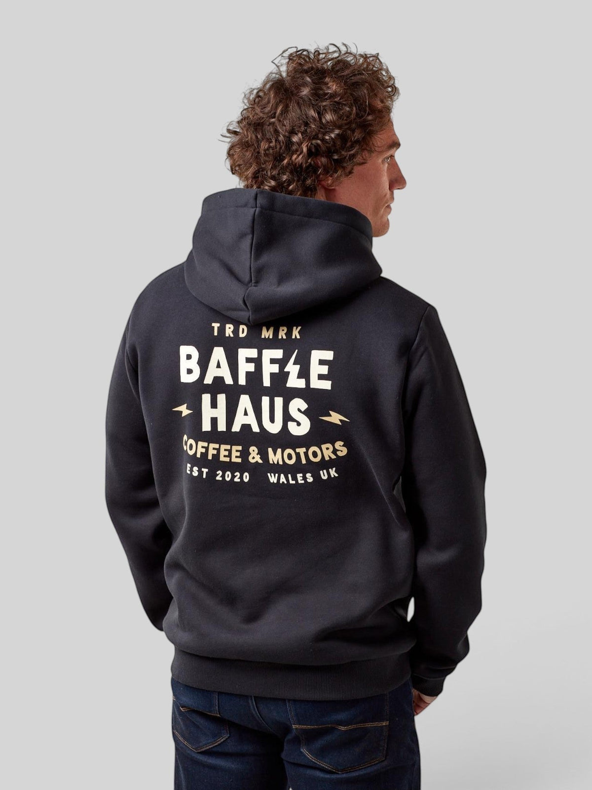 Model wearing a jet black Baffle Haus heavyweight cotton-blend hoodie with Coffee & Motors graphic on the back