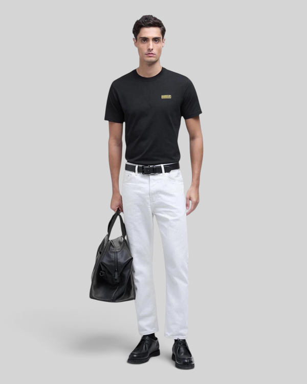 Baffle Haus black cotton crew neck t-shirt with small yellow chest logo worn by a male model with white jeans