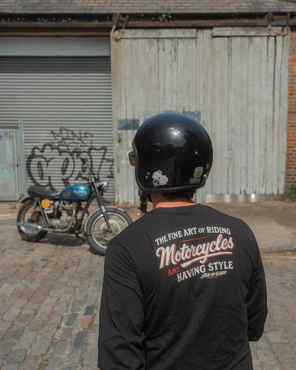 Baffle Haus black long sleeve cotton tee with vintage sign painting style graphic on back, worn by a motorcyclist.