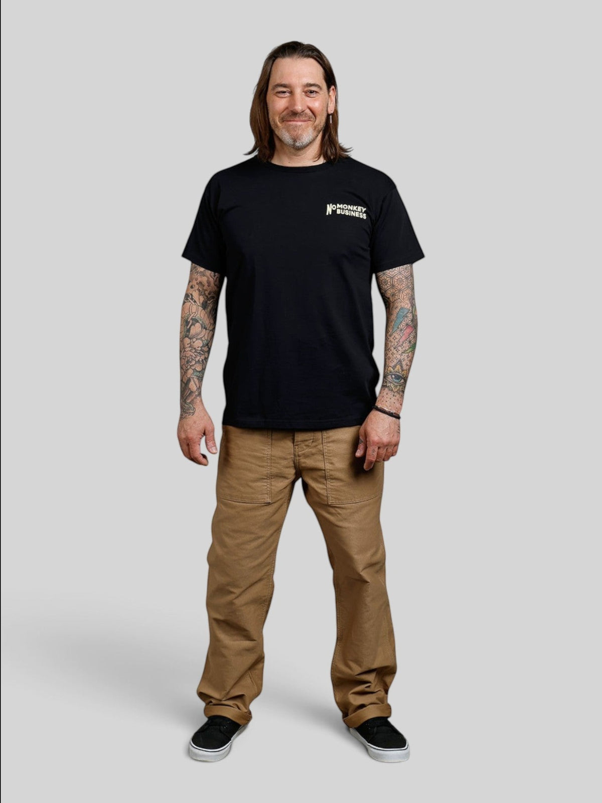Baffle Haus black 100% cotton sports tee with Monkey Business graphic worn by a tattooed man in brown work pants