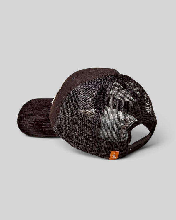 Baffle Haus black trucker cap with breathable mesh back, structured front panel, and small orange logo tab.