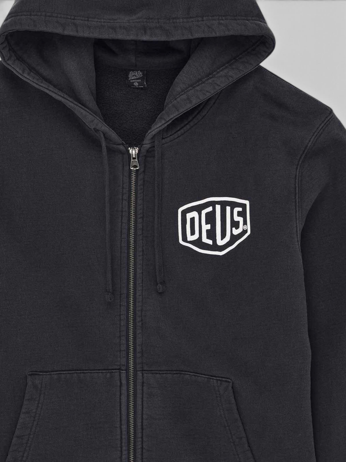 Baffle Haus black garment dyed zip hoodie featuring an embroidered white Deus shield logo on the chest