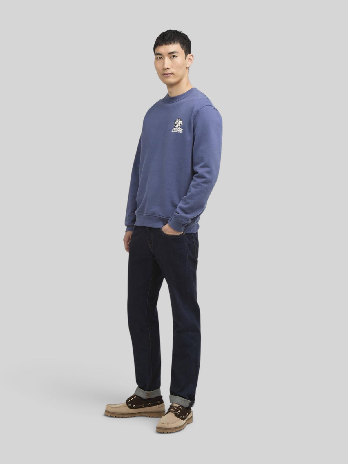 Model wearing a Baffle Haus International Talisman blue cotton graphic sweatshirt with ribbed trim and dark jeans
