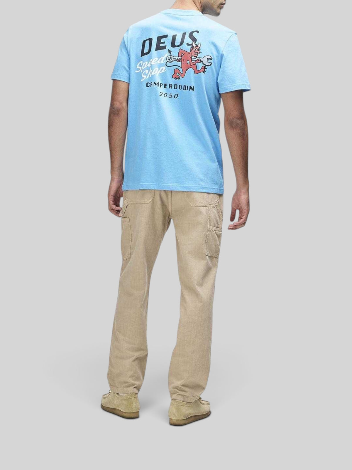 Baffle Haus model wearing a Bonnie Blue Deus short sleeve tee with back graphic print and beige utility trousers.