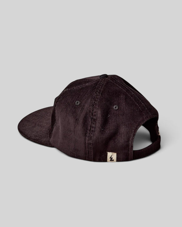 Baffle Haus dark brown corduroy panel cap with a structured design and small logo tab on the back strap.