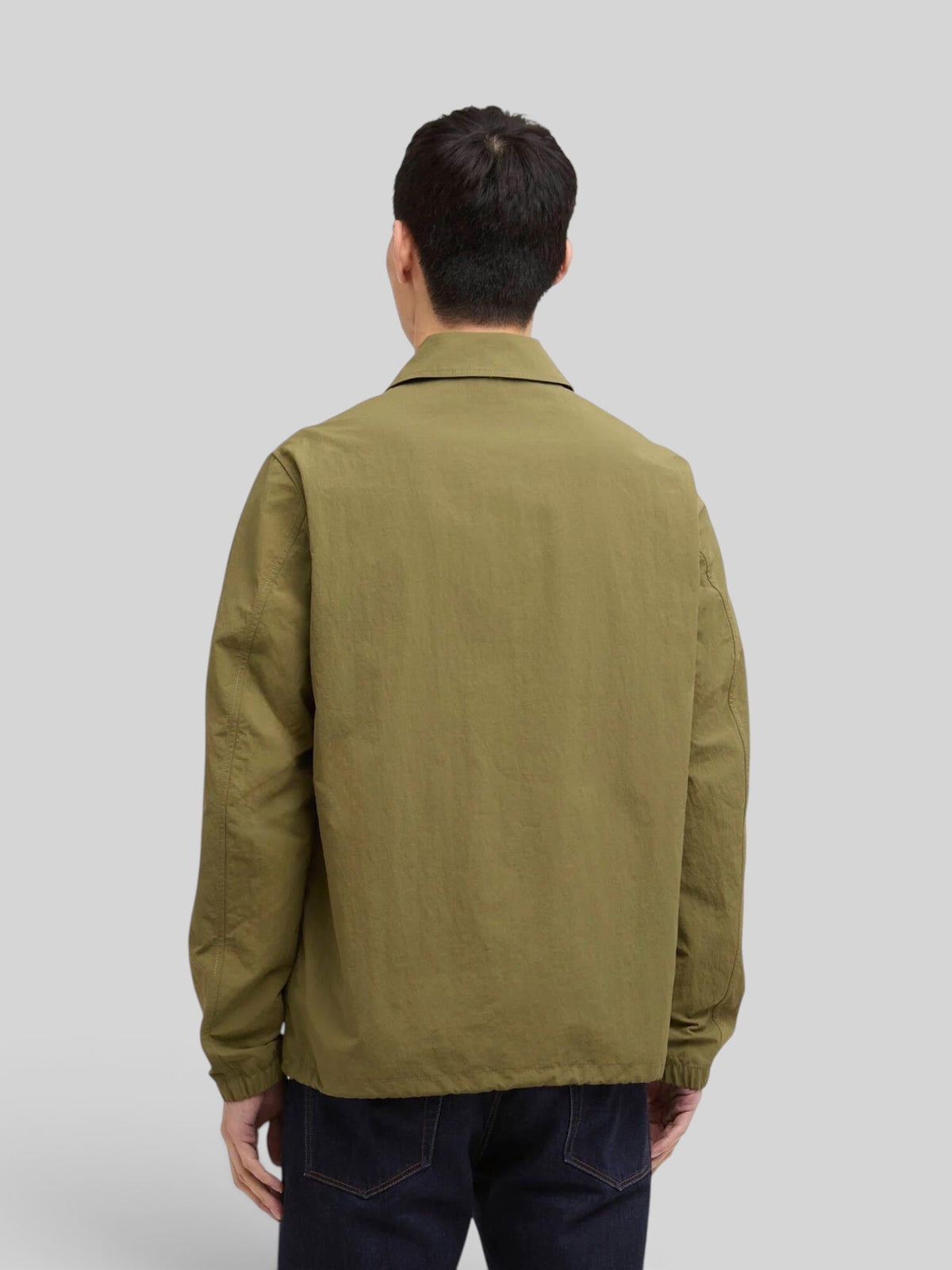 Back view of a man wearing a Baffle Haus International Coach Casual Jacket in burnt olive with a classic collar.