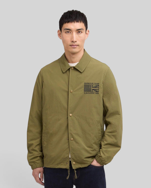 Baffle Haus International Coach Casual Jacket in burnt olive with stud front, sit-down collar, and Steve McQueen logo.