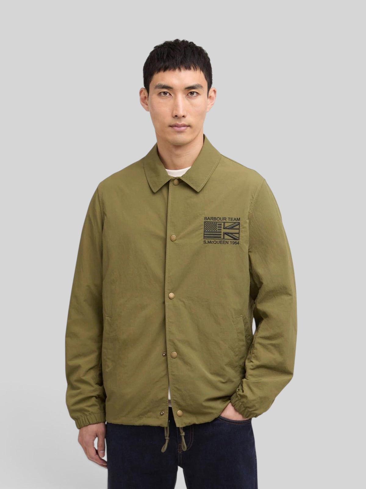 Baffle Haus International Coach Casual Jacket in burnt olive with stud front, sit-down collar, and Steve McQueen logo.