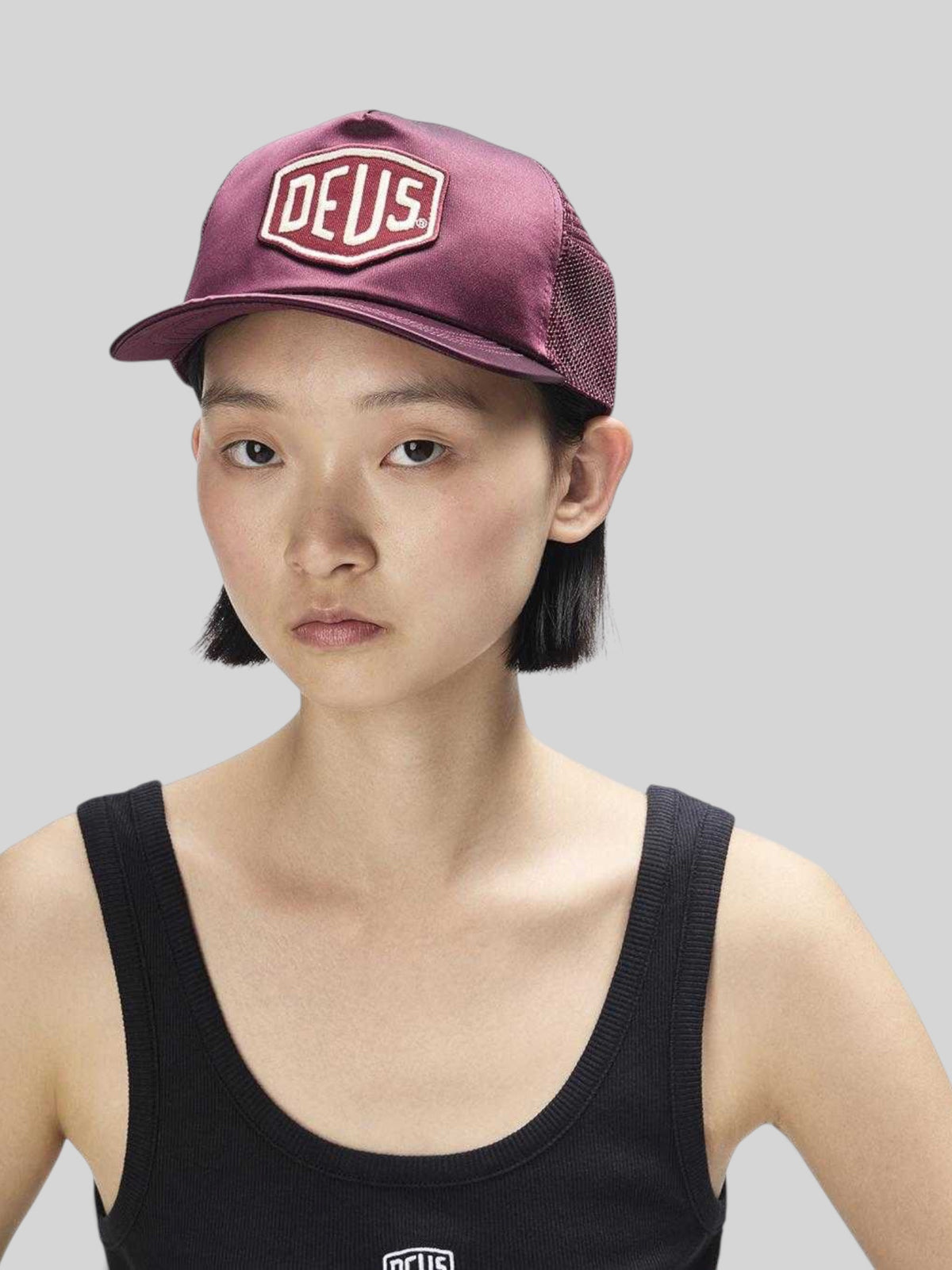 Baffle Haus Paris Shield trucker cap in cabernet red satin and mesh with a front logo patch worn by a woman