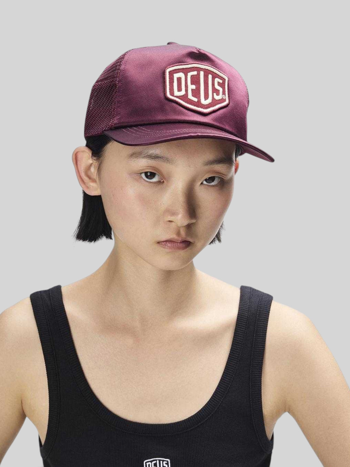 Baffle Haus Paris Shield trucker cap in cabernet red satin and mesh with a front logo patch worn by a woman