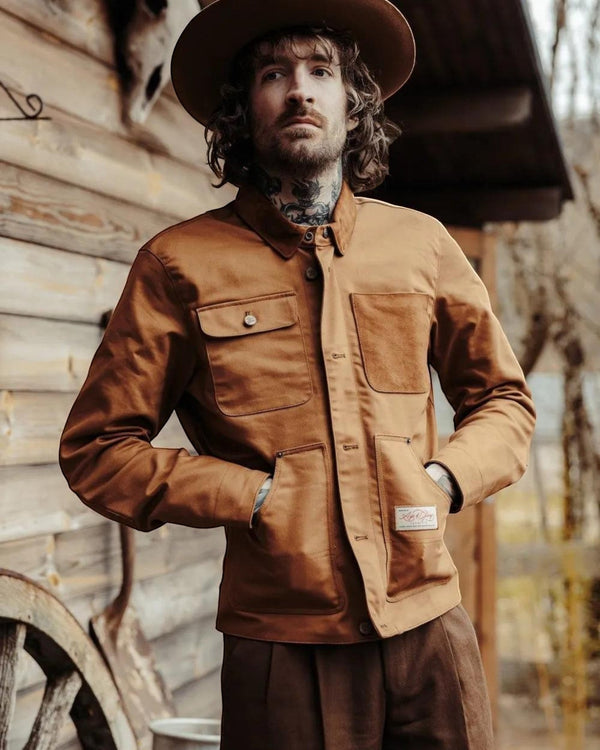 Baffle Haus Craftsman jacket in caramel 14 oz fabric with antique brass buttons worn by a man in a rustic setting
