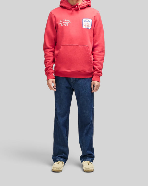 Baffle Haus cherry red organic cotton fleece hoodie with embroidered chest art and kangaroo pocket on a model