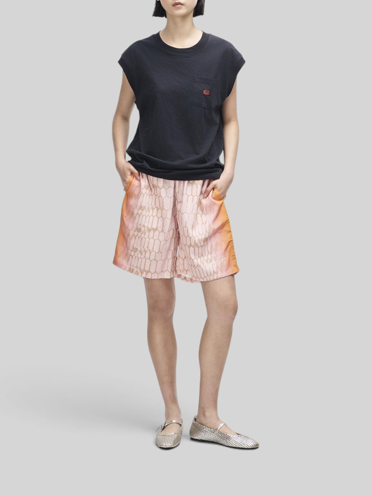 Baffle Haus Christine tank in black with cap sleeves and chest pocket worn with patterned pink shorts