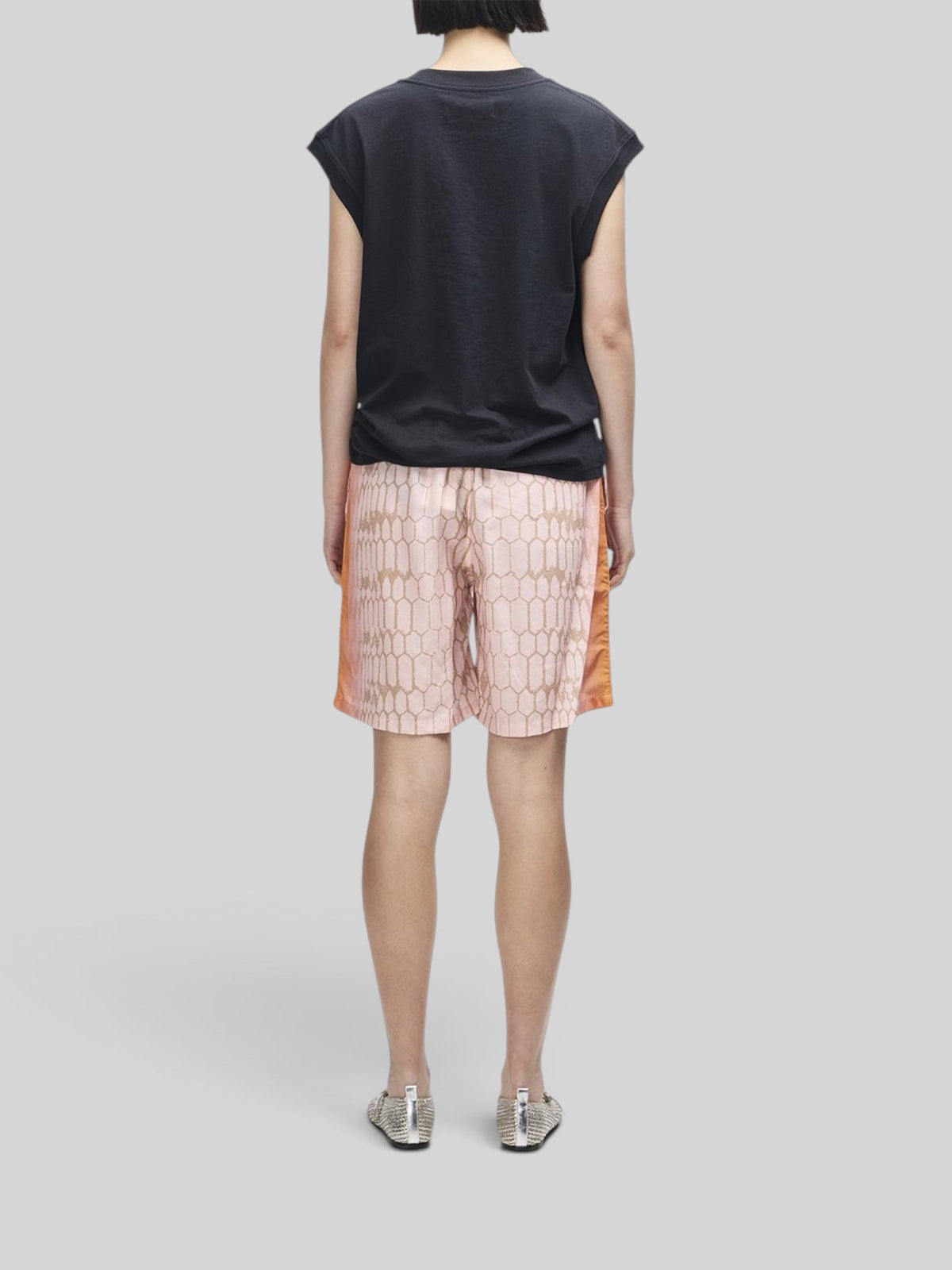 Baffle Haus Christine tank in black worn with patterned pink shorts, back view showing cap sleeve and ribbed neck