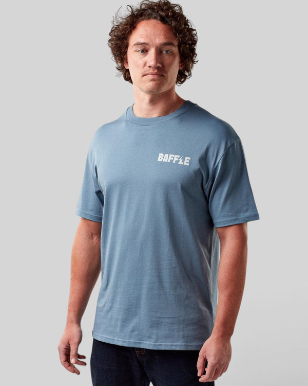 Baffle Haus Flags Tee in coastal blue cotton with white chest logo worn by a male model against a grey background