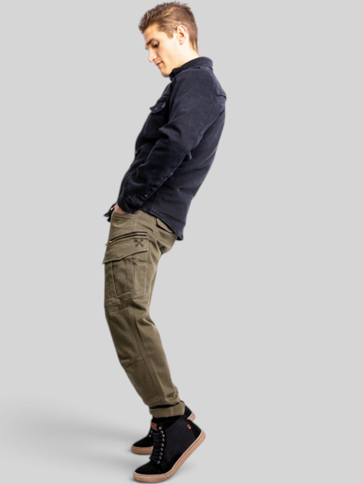 Baffle Haus Defender Mono olive cargo motorcycle jeans worn by a man in a black shirt, side profile view