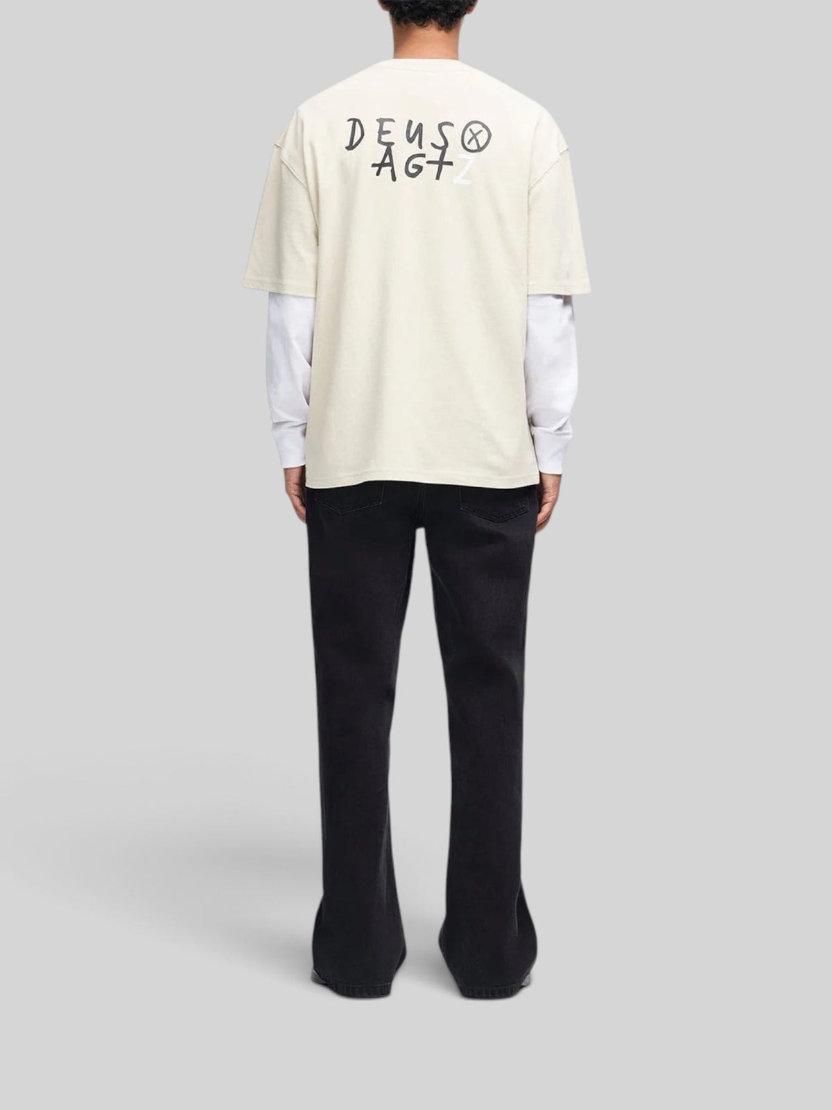 Baffle Haus Deus x AGTZ oversized bone white cotton t-shirt with back graphic print worn over a long sleeve shirt