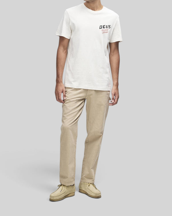 Baffle Haus model wearing a dirty white regular fit short sleeve tee with Deus Speed Shop chest graphic
