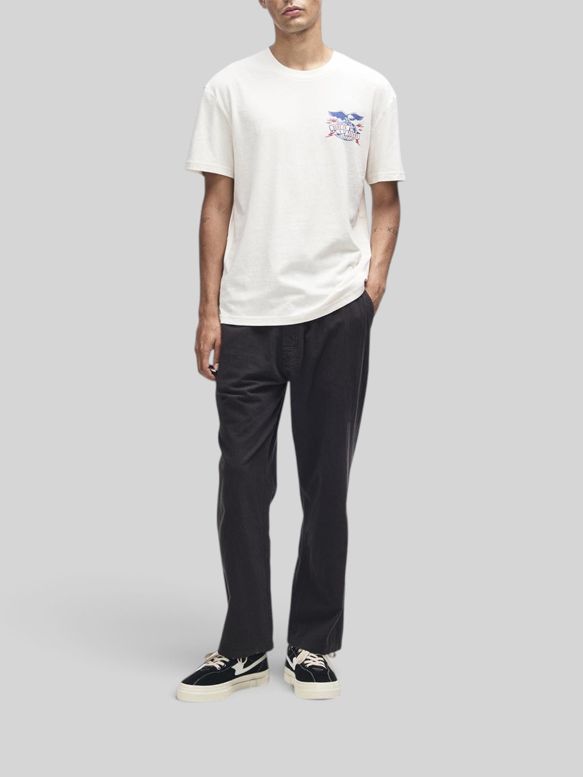 Baffle Haus model wearing a dirty white box fit t-shirt with graphic chest print and recycled cotton blend fabric.