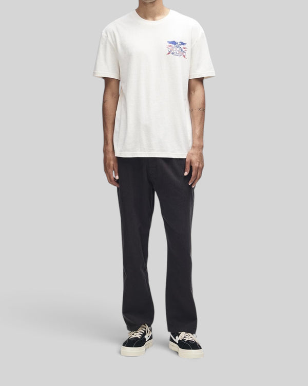 Baffle Haus Claw-Some Whizz Tee in dirty white with chest graphic, worn by a model with black trousers and sneakers.