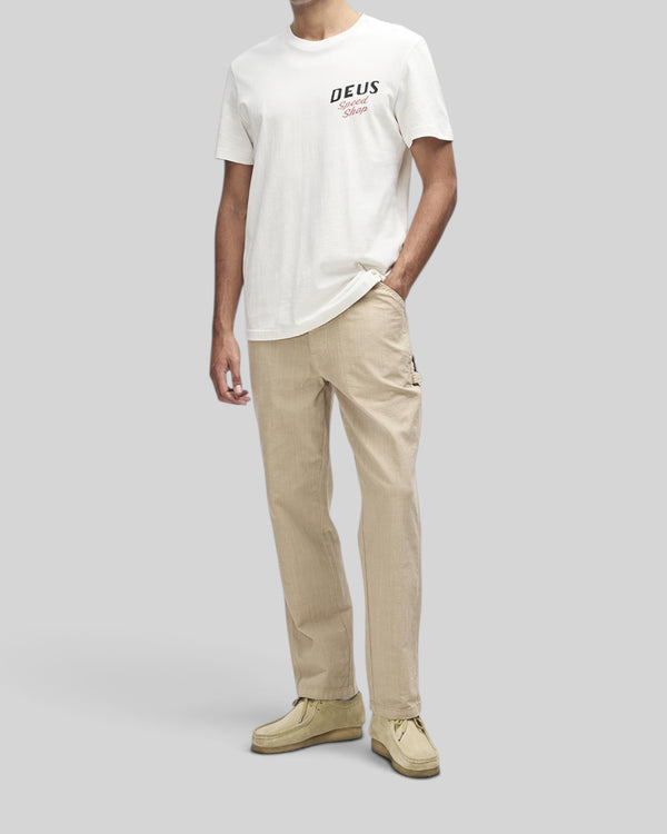 Baffle Haus Dogleg Tee in dirty white organic cotton with Deus Speed Shop chest graphic on a male model