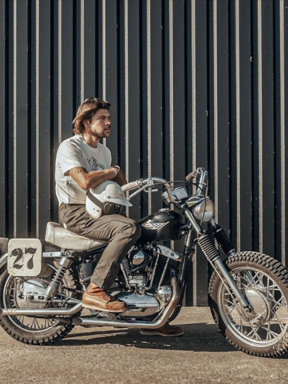 Baffle Haus El Mirage off-white cotton t-shirt with vintage winged wheel graphic worn by a man on a classic motorcycle