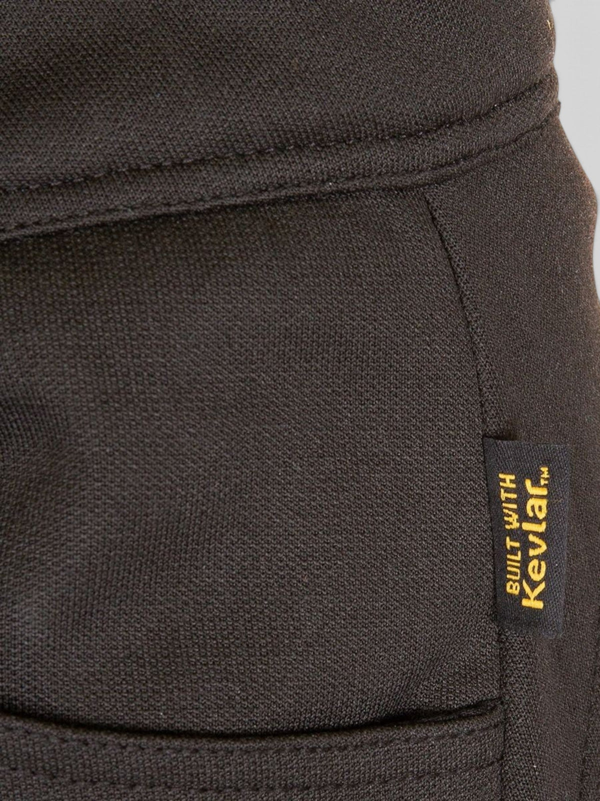 Close-up of black Baffle Haus Elana D30 legging fabric with a yellow Built With Kevlar tag.