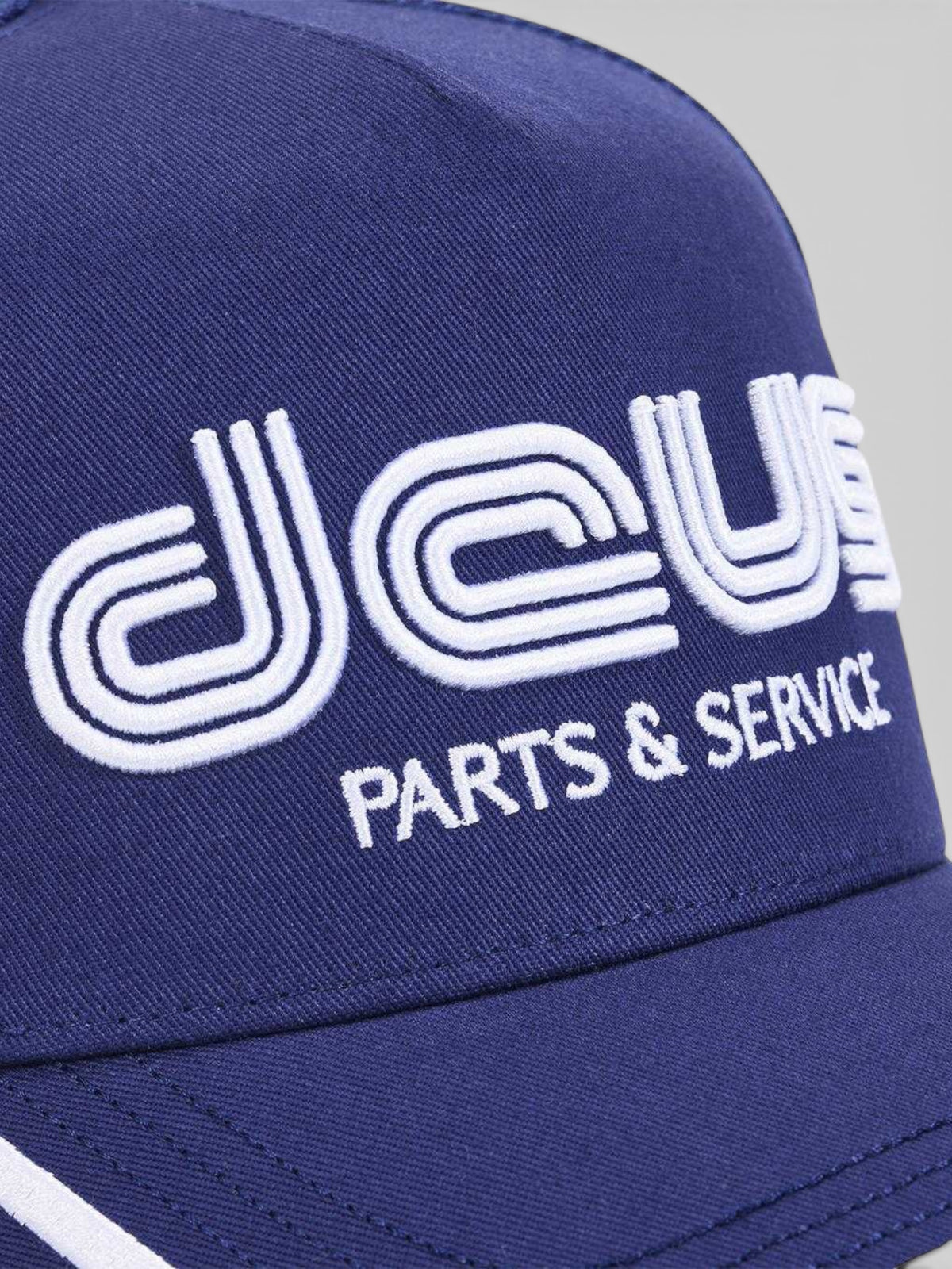 Baffle Haus Double Track Trucker hat in estate blue cotton twill with white embroidered Deus logo and visor detail