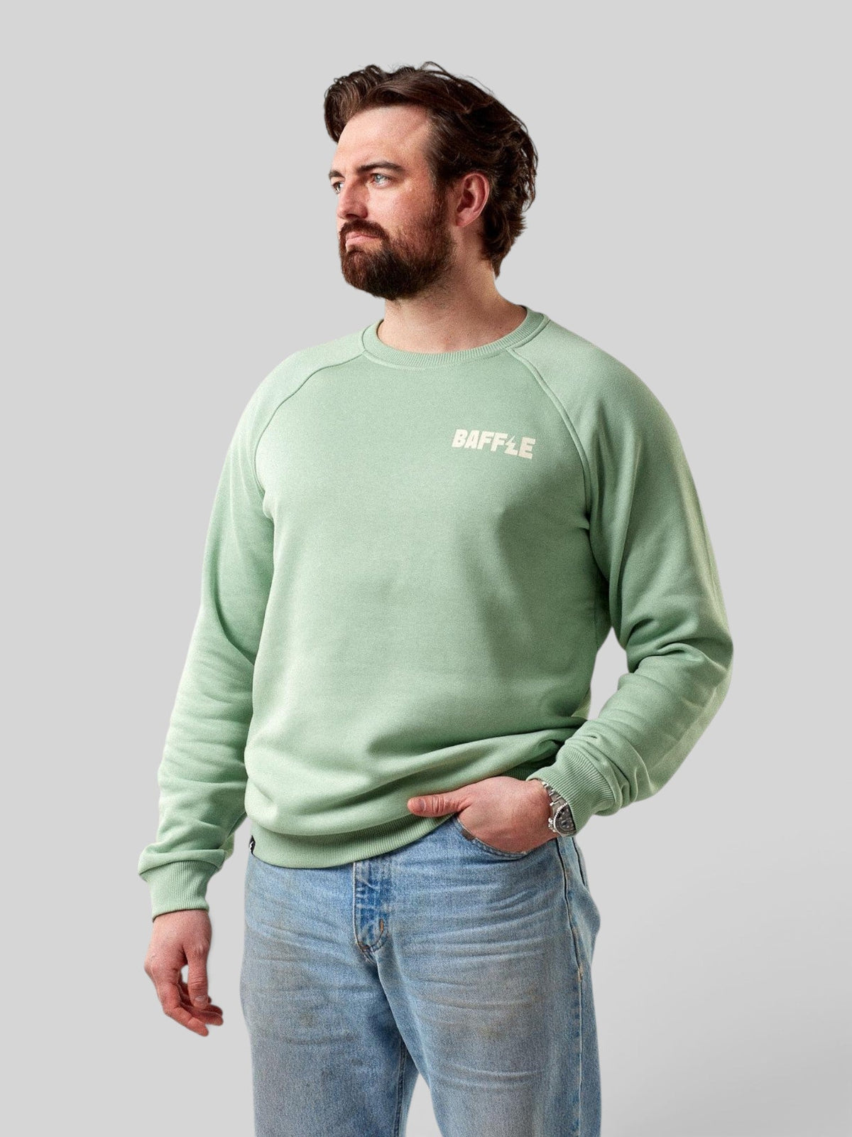 Baffle Haus Flags sweatshirt in granite green with raglan sleeves and white chest logo worn by a bearded model