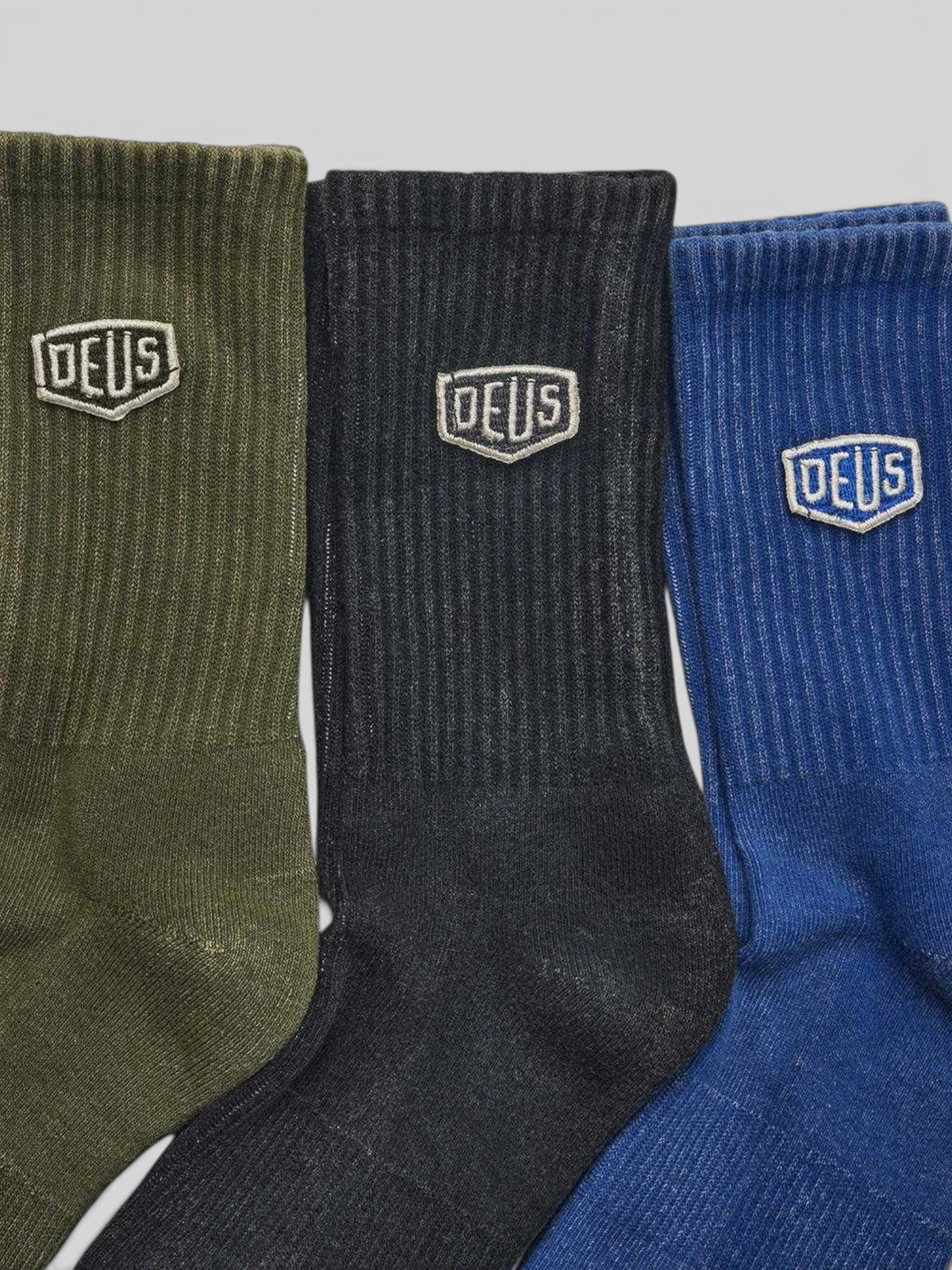 Baffle Haus 3-pack of garment dyed cotton blend socks in olive, black, and blue with tonal Deus shield embroidery.