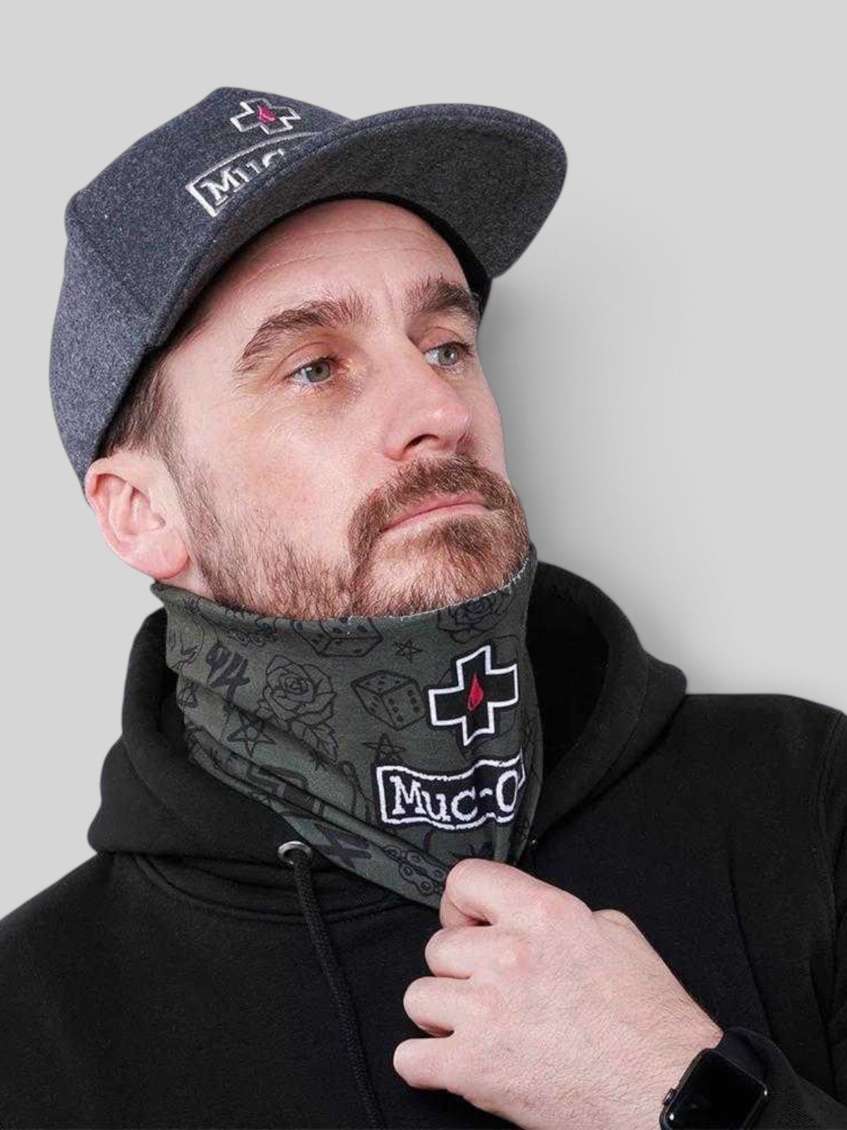 Baffle Haus green punk print lightweight neck gaiter worn by a man in a black hoodie and grey cap