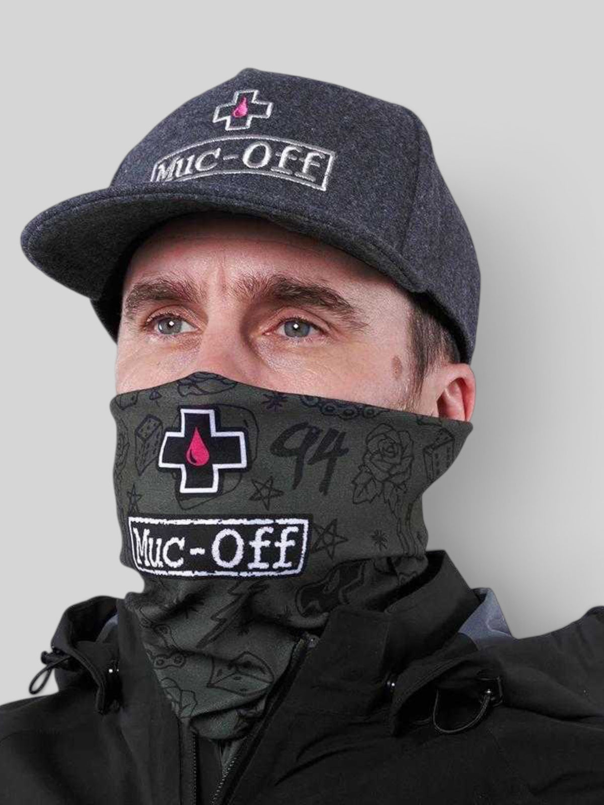 Baffle Haus green punk lightweight neck tube featuring Muc-Off branding and graphic patterns worn by a man in a cap.