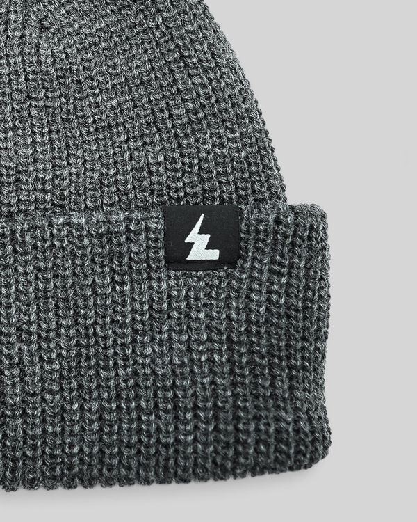 Baffle Haus grey acrylic knit beanie with a woven logo label on the cuff, featuring a classic ribbed texture.