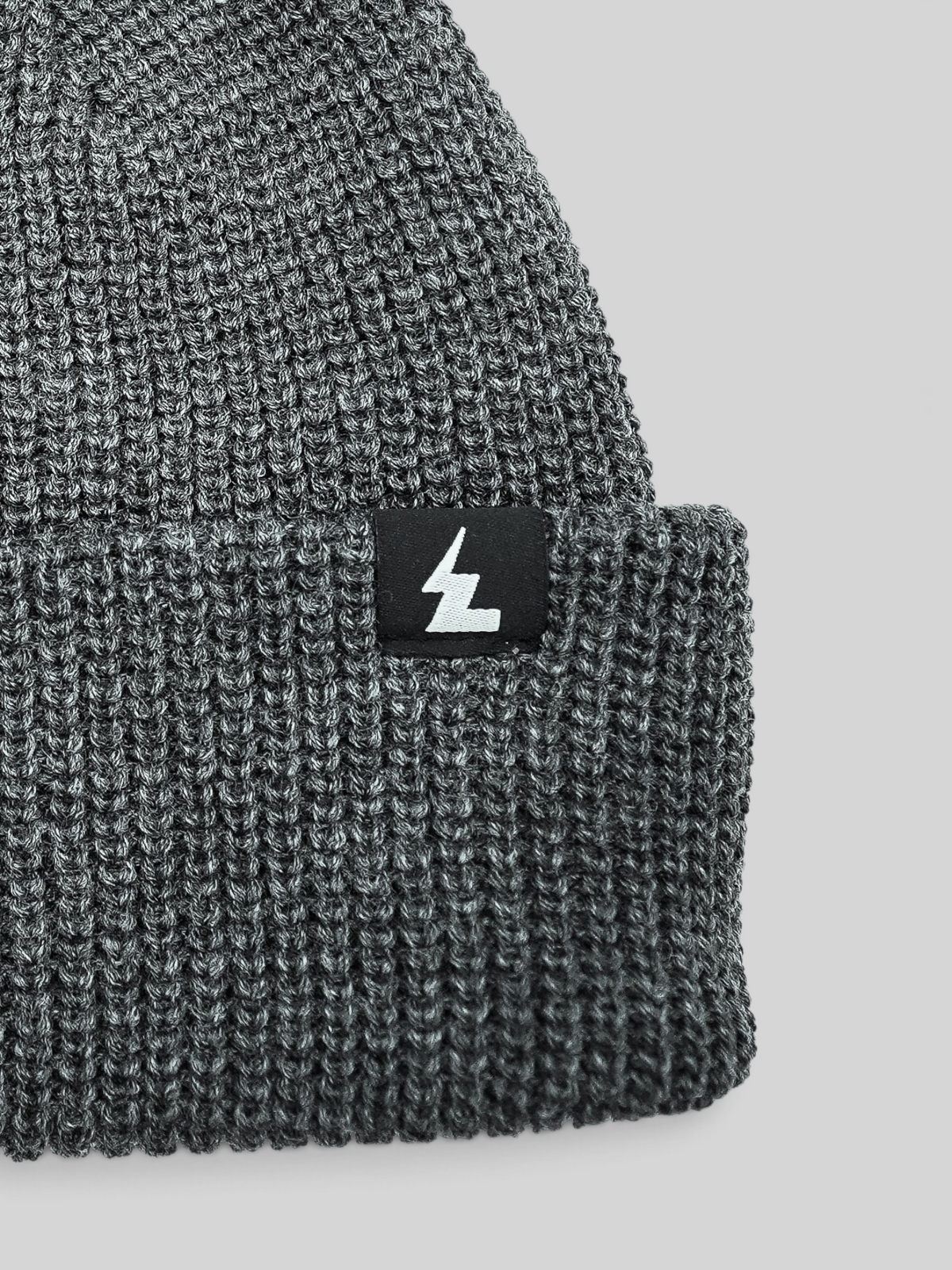 Baffle Haus grey acrylic knit beanie with a woven logo label on the cuff, featuring a classic ribbed texture.