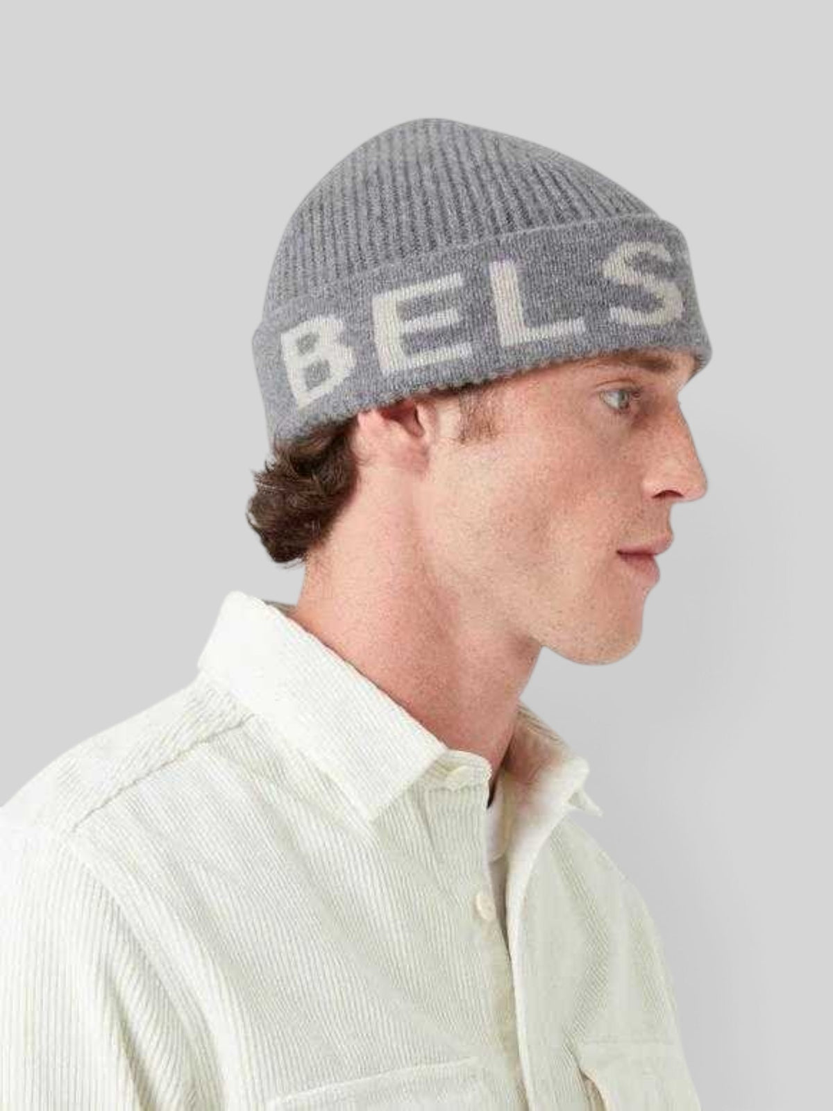 Baffle Haus grey lambswool beanie with silver intarsia logo worn by a man in profile view