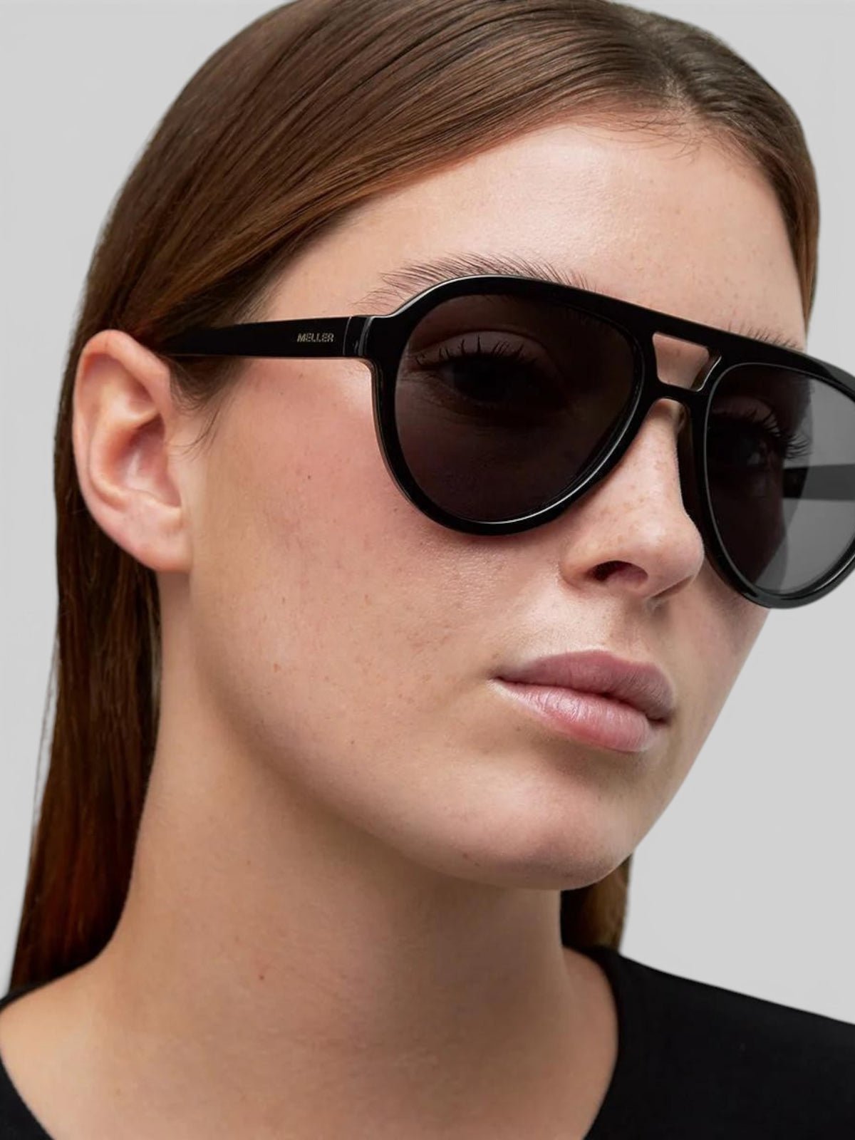 A woman wearing Baffle Haus KENA black aviator sunglasses with a double bridge and polarized lenses.