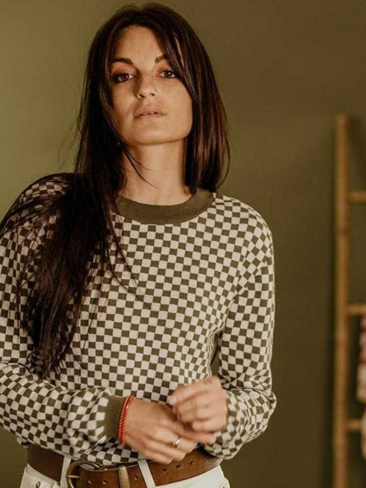 Baffle Haus khaki and white checkerboard knitted jumper with ribbed collar and cuffs worn by a woman