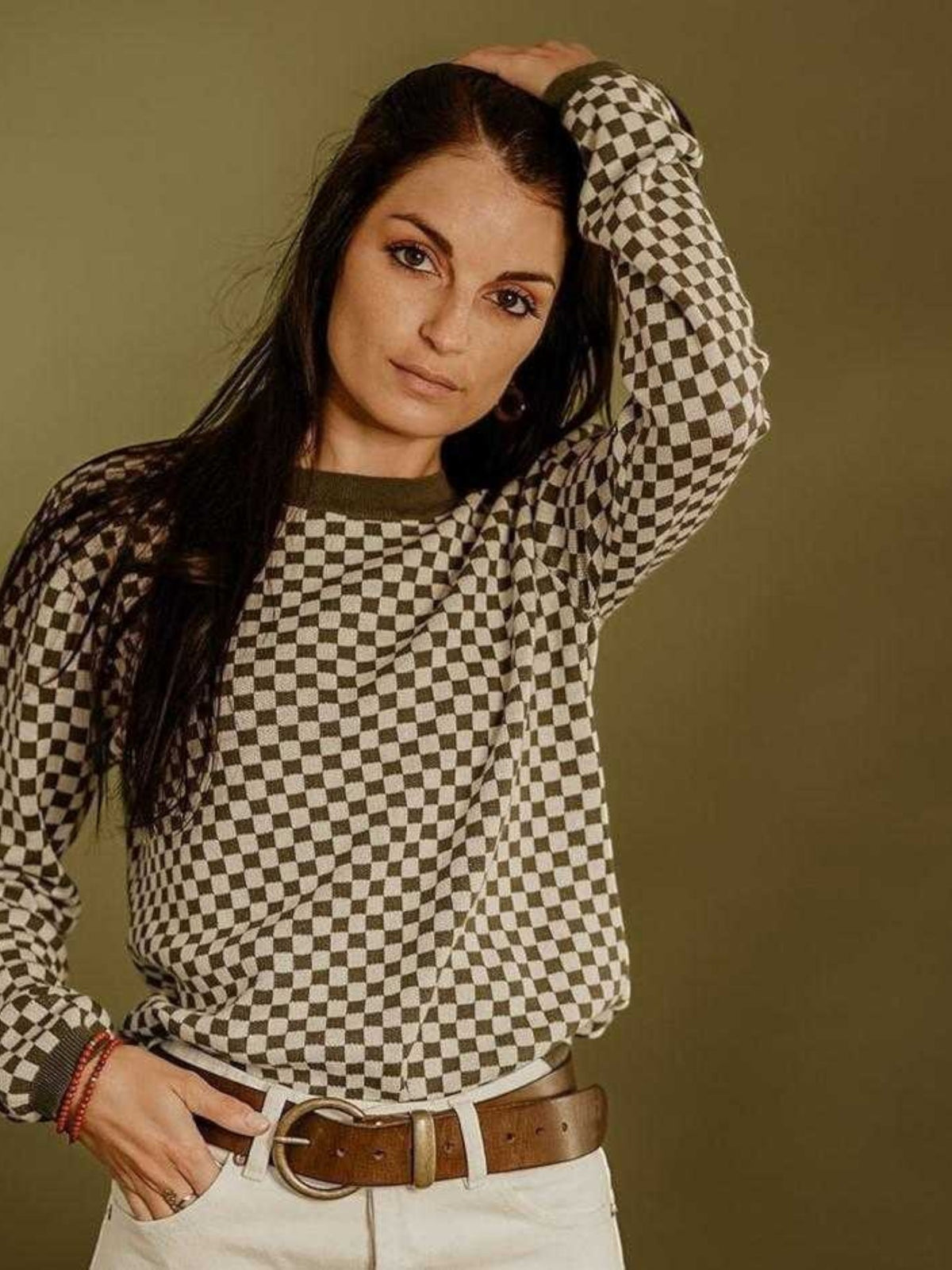 Baffle Haus khaki knitted jumper with a retro checkerboard pattern, ribbed collar, and cuffs worn by a woman