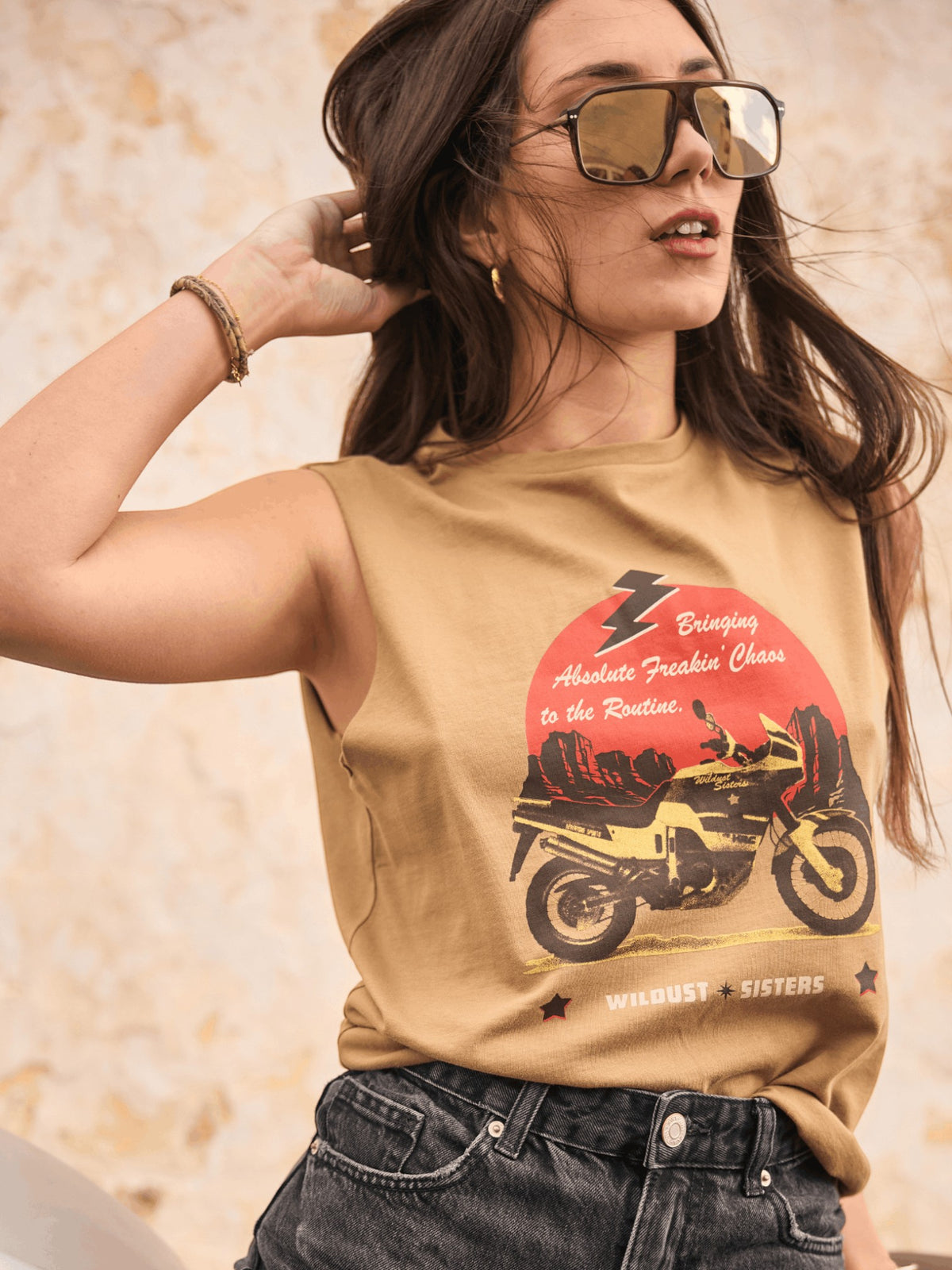 Baffle Haus khaki cotton tank top featuring a motorcycle graphic, worn by a woman with sunglasses outdoors.